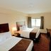 Cobblestone Inn & Suites - Denison guest room with two beds, desk, TV, and window view