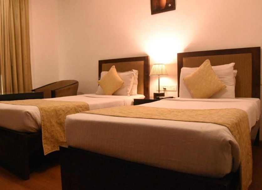 Hotel Clark Inn Kaushambi in Ghāziābād: twin beds, bedside lamp and window with curtains