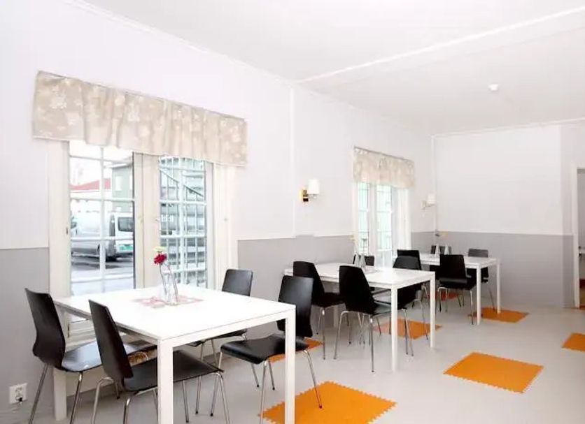 Airport Motel & Apartment in Gardermoen breakfast room with white tables, black chairs, and orange floor mats