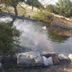 Super 8 by Wyndham Kenedy pond with stone border, wooden bridge and fountain in a landscaped garden