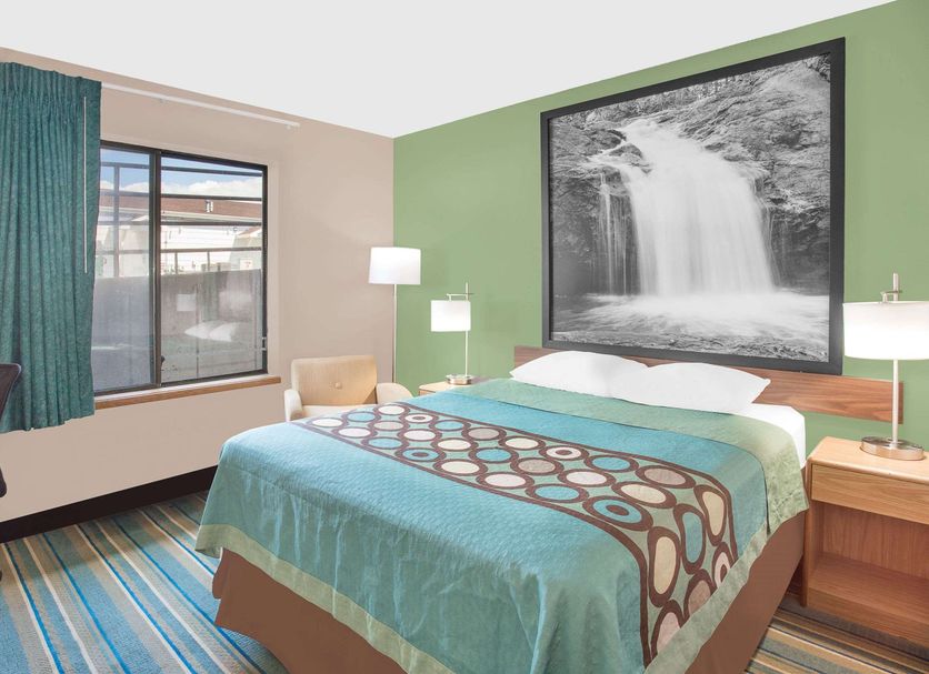 Super 8 by Wyndham Beaver Dam guest room with king bed, waterfall wall art, and window view