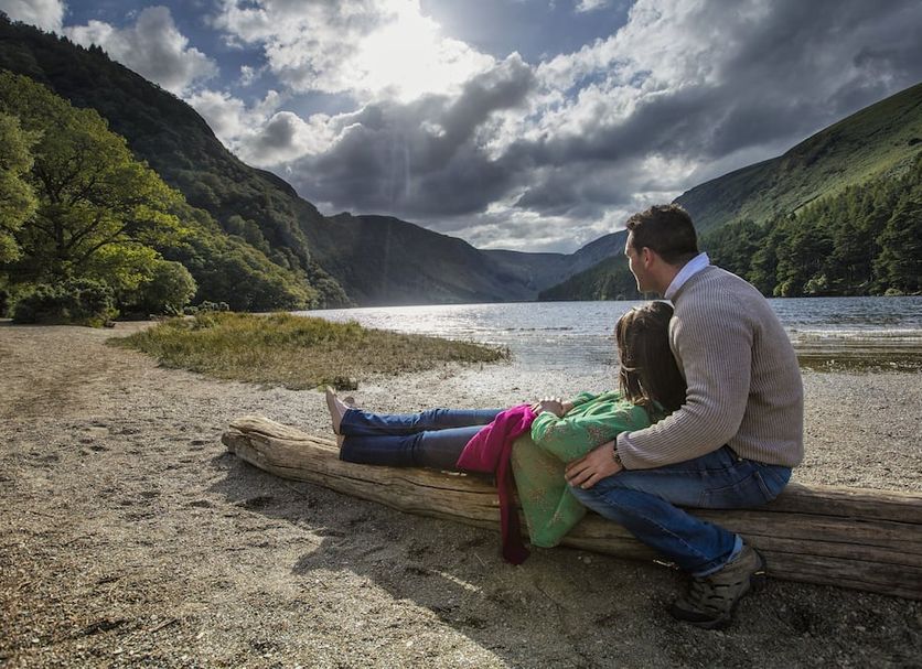Woodenbridge Hotel, Arklow: couple sitting on a log by a lake in a mountain valley