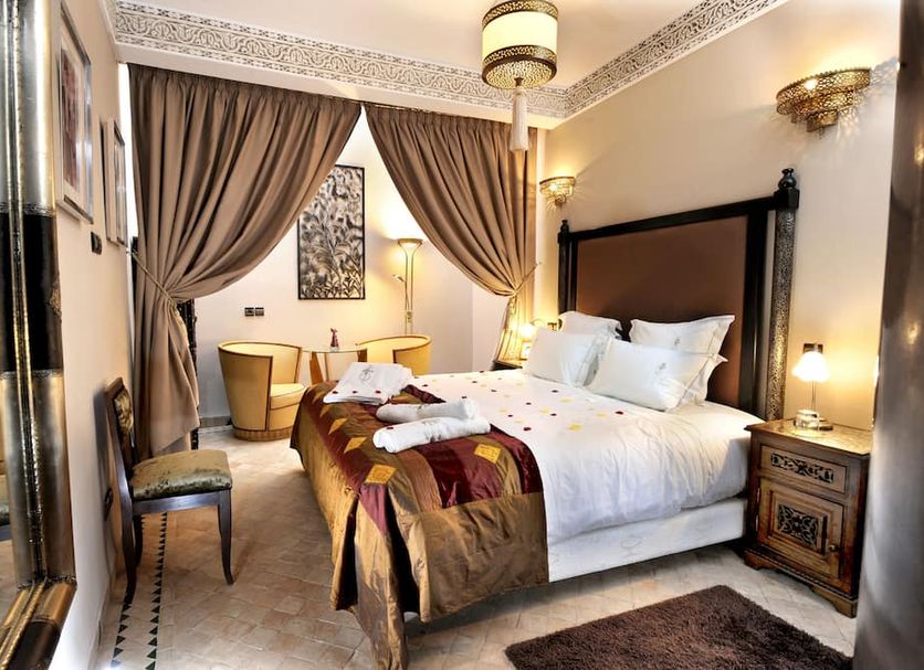 Riad Belle Epoque Marrakech guest room with four-poster bed, draped curtains, and seating area
