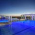 Pumicestone Blue in Caloundra rooftop pool with blue-lit spa and city views at dusk