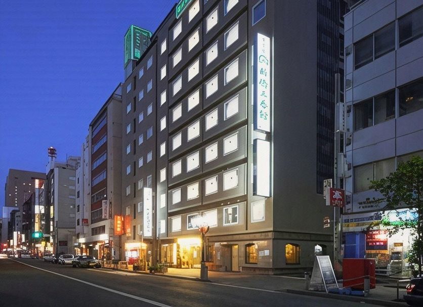 Hotel Shimbashi Sambankan in Tokyo, exterior at dusk on a city street with lit windows