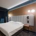 Artis Loft Hotel in Mszczonów guest room with double bed, chair, desk and modern wall lighting