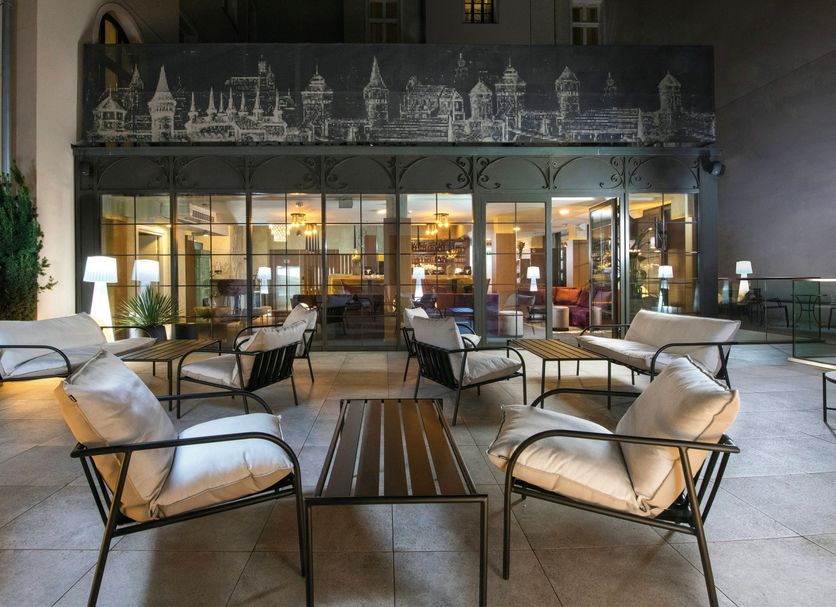 Leonardo Boutique Hotel Krakow Old Town courtyard seating area with outdoor lounge chairs and glass-front entrance