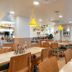 Bloom Hotel - Sg Highway, Ahmedabad restaurant with wooden tables, pendant lights, and large windows