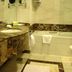 Sharjah Palace Hotel bathroom in Sharjah with marble vanity, mirror, and bathtub