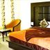 Hotel The Great Ananda, Haridwar: a double bed with tufted headboard, chair and side table