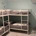 Svea Hostel Stockholm dorm room with metal bunk beds, desk, chair, fan, and tiled floor