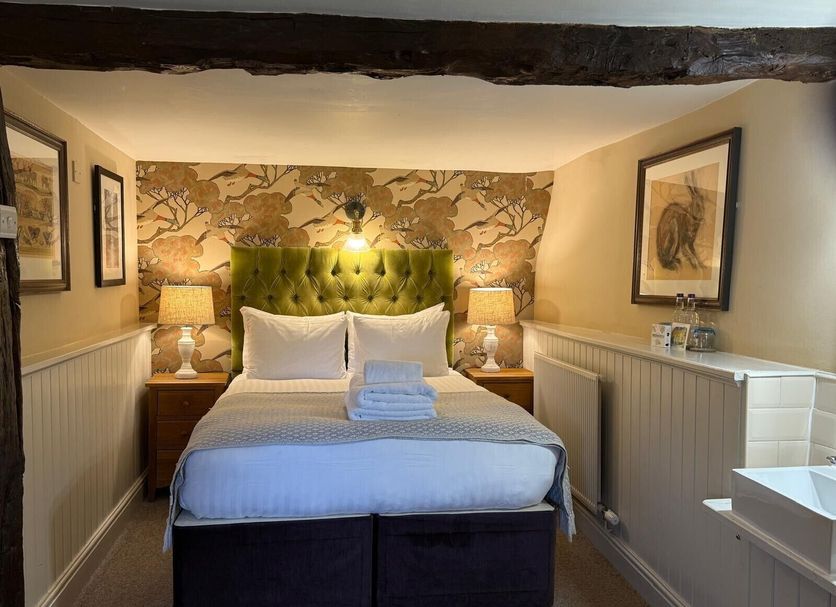 The Falkland Arms, Chipping Norton: cozy guest room with a double bed, bedside lamps, and patterned headboard