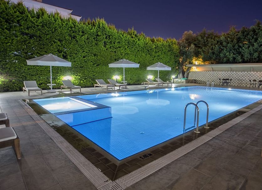 Cilek Marina Hotel in Cesme with a lit outdoor pool, sun loungers, and umbrellas at night