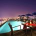 Yogi Executive, Navi Mumbai rooftop pool with city skyline and dining table at dusk