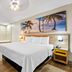 Days Inn by Wyndham Jacksonville NC guest room with king bed, palm wall art, and wooden floor