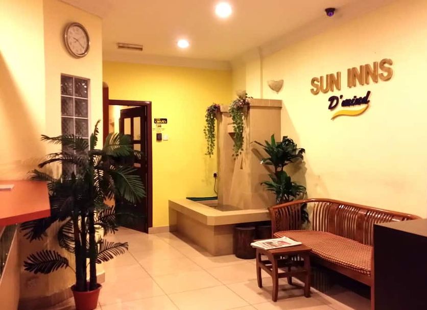 Sun Inns Dmind Seri Kembangan lobby with wooden bench seating, potted plants, and warm yellow lighting