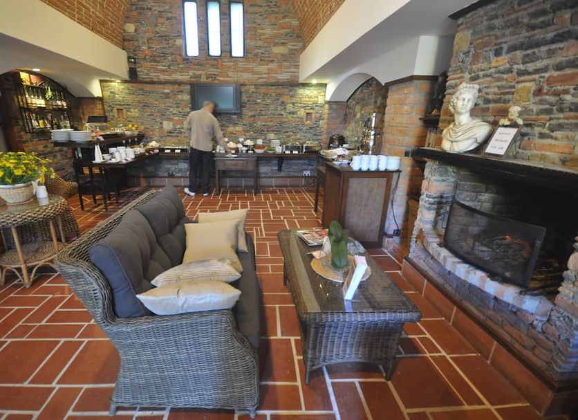 El Vino Hotel & Suites Bodrum lounge with stone fireplace, wicker seating, and buffet area