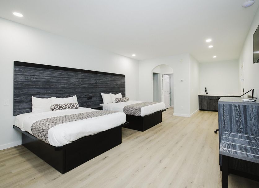 Sapphire Inn and Suites Deer Park guest room with two beds, TV, desk, and light wood flooring