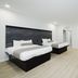 Sapphire Inn and Suites Deer Park guest room with two beds, TV, desk, and light wood flooring