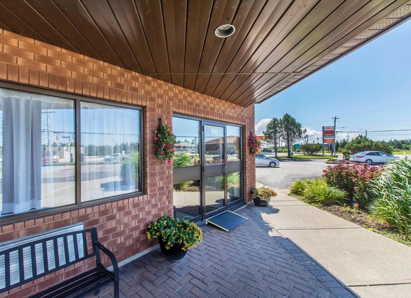 Comfort Inn Yarmouth exterior entrance with brick facade, glass doors, bench, and sidewalk by the road.