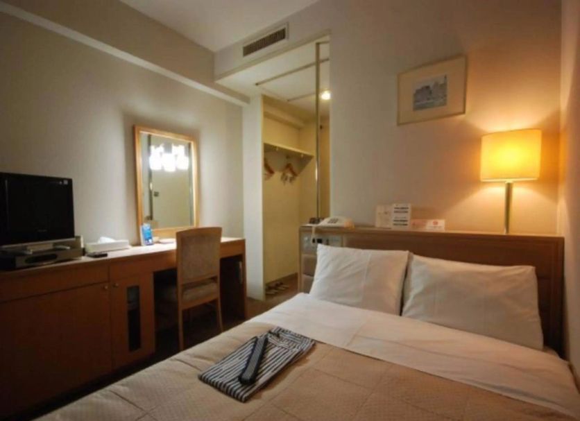 Central Hotel Fukuoka guest room in Fukuoka with bed, desk, mirror and warm bedside lamp