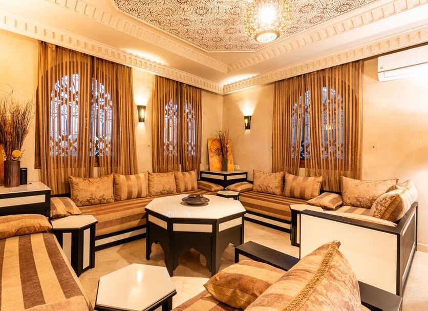 Riad Ushuaia - Centre Marrakech lounge with ornate ceiling, carved windows, and beige seating