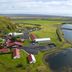 Hotel Katla by Keahotels in Vik with red-roofed buildings beside water and green hills