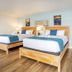 Surf House in Hampton guest room with two wooden beds, blue bedding, and light blue walls
