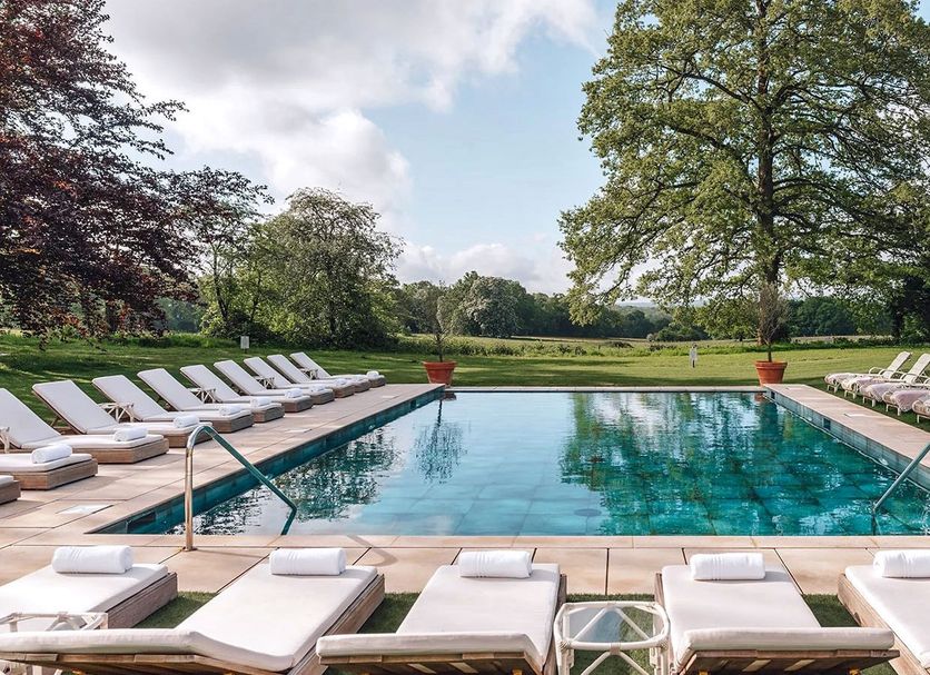 The Alfriston in Polegate with an outdoor pool and sun loungers in a landscaped garden