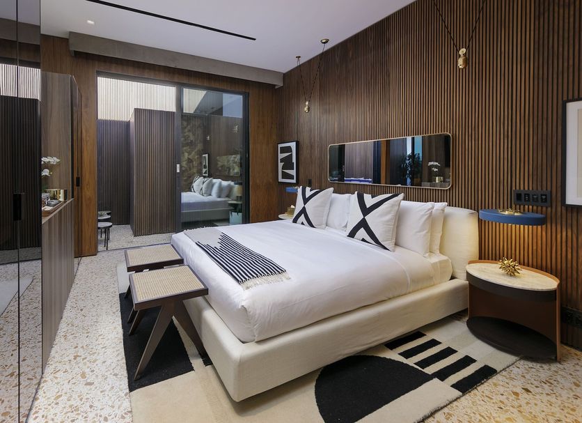 L'Horizon Resort & Spa Palm Springs bedroom with king bed, wood-paneled walls, and patio view