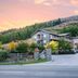 Shotover Lodge in Queenstown set in front of wooded hills at sunset with gated entrance
