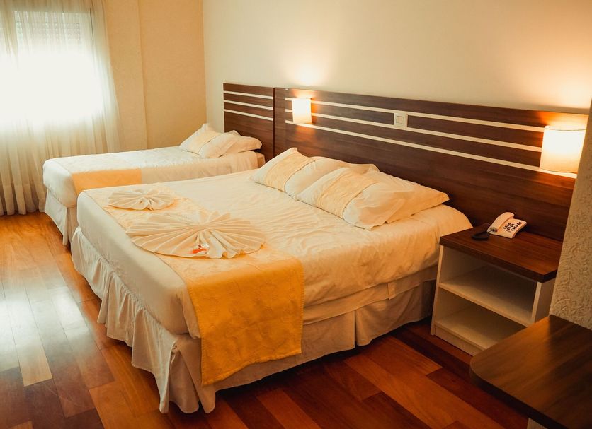 Hotel Imperial in Quatro Barras guest room with two beds, wood floor, and window light