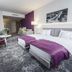 Hotel Metropolitan Rzeszow guest room with king bed, purple accents and sitting area
