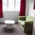 Backpackers Central Hamilton room with green sofa, TV, coffee table and window with red curtains