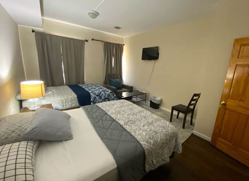 Cjay Homes in Jersey City guest room with two beds, wall-mounted TV, curtains, and wooden door