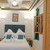 Riad Zanouba in Marrakech, a cozy guest room with twin beds, teal pillows, wall lights, and patterned ceiling.