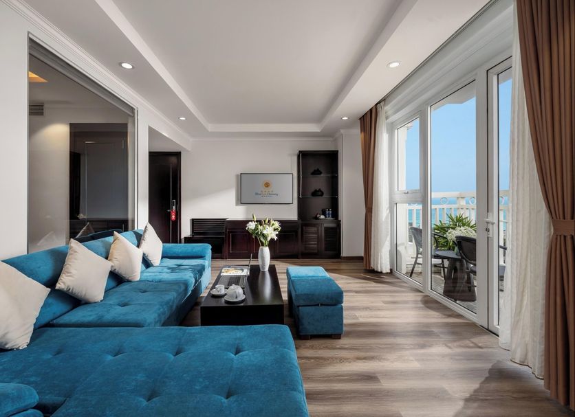 Bluesun Danang Beach Hotel in Da Nang living room with ocean-view balcony and blue sectional sofa