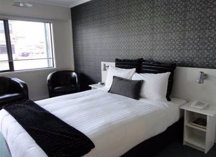 Abode On Courtenay Motor Inn, New Plymouth guest room with queen bed, window and black chairs