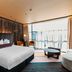Naumi Hotel Wellington in Wellington guest room with king bed, floor-to-ceiling windows and lounge chairs