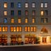 The Flat Iron Hotel in Asheville exterior at dusk with warmly lit windows and street-level patio seating