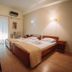 Hotel King Pyrros in Ioánnina: simple twin-bed guest room with desk, wood floors, and balcony door