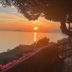Sunset sea view from La Maliosa D' Arienzo in Positano, with terrace flowers and a tree-framed horizon.