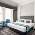 Cairn Hotel Newcastle Jesmond room with king bed, teal chairs, and large window in Newcastle upon Tyne