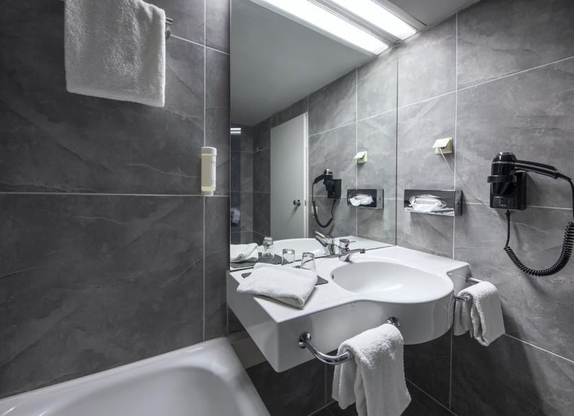 Achat Hotel Monschau bathroom with bathtub, wall-mounted sink, large mirror and towel warmer in Monschau