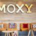 MOXY Rust lobby seating with colorful chairs and wooden wall sign in Rust