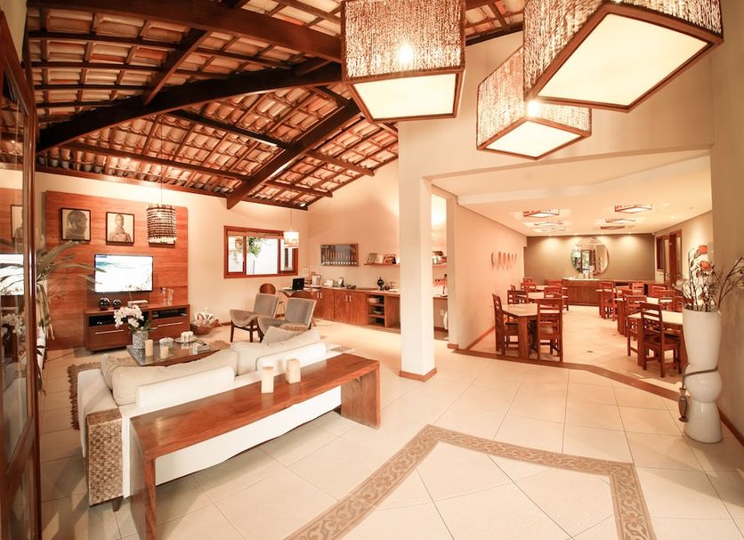 Barcaça Pousada in Itacaré lobby with seating area, dining tables, and rustic wood-beamed ceiling