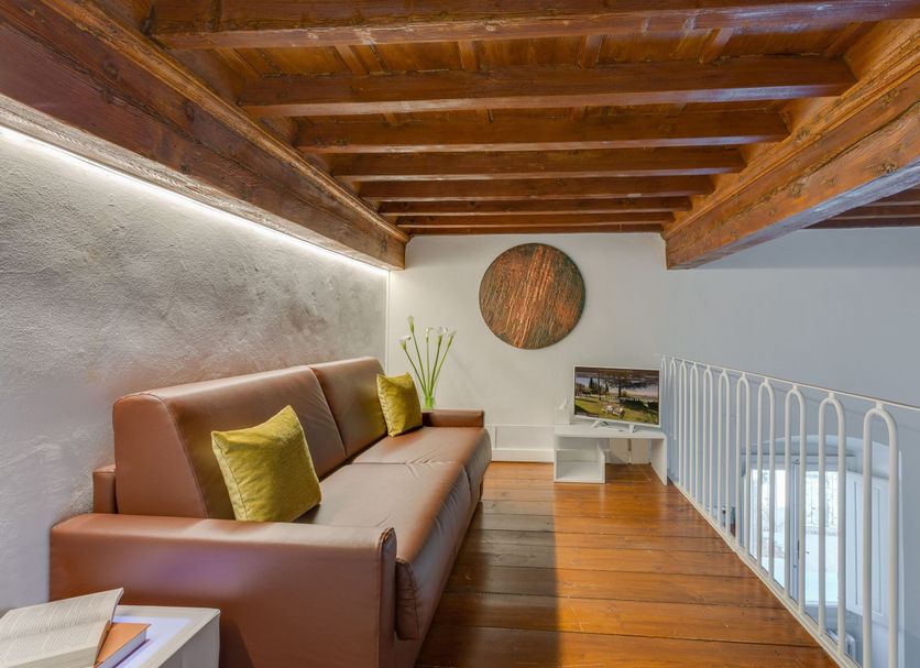 Villa I Barronci Resort & Spa loft lounge with leather sofa, wood beams and railing in San Casciano Val Di Pesa