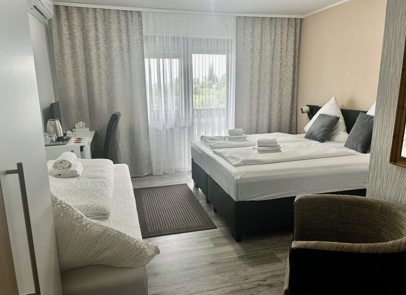 Hotel Hasselberg, Kaiserslautern guest room with double bed, sofa, desk and balcony doors