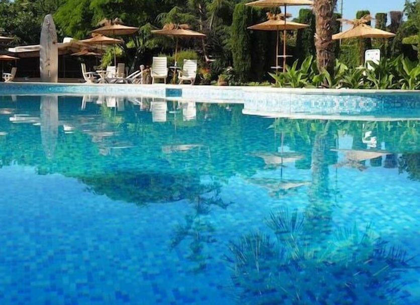 Joya Park Hotel in Varna with outdoor pool, sun umbrellas and lush garden setting