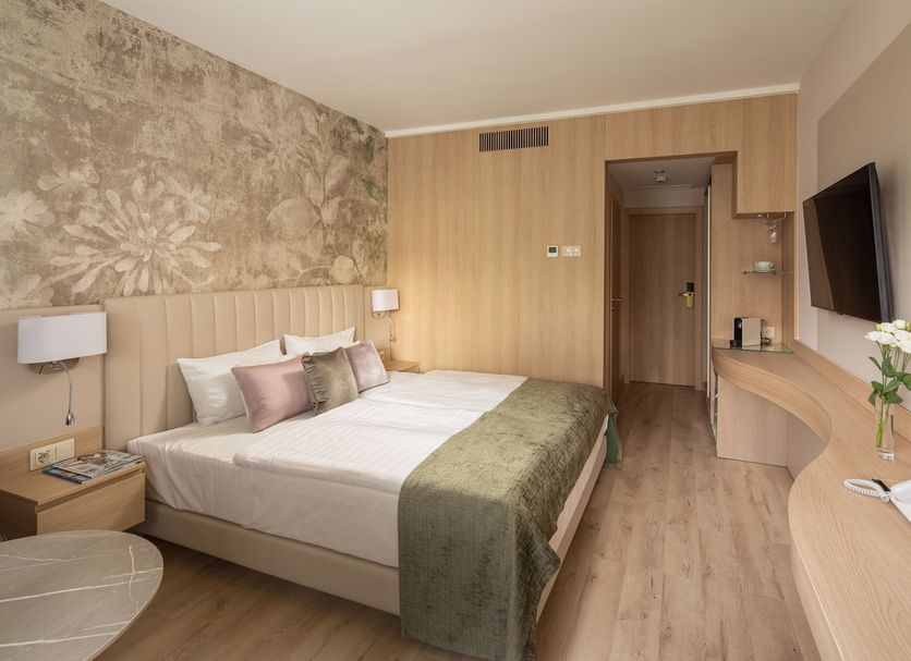 Hotel Carbona Thermal Spa Hévíz guest room with double bed, wall-mounted TV and wood accents